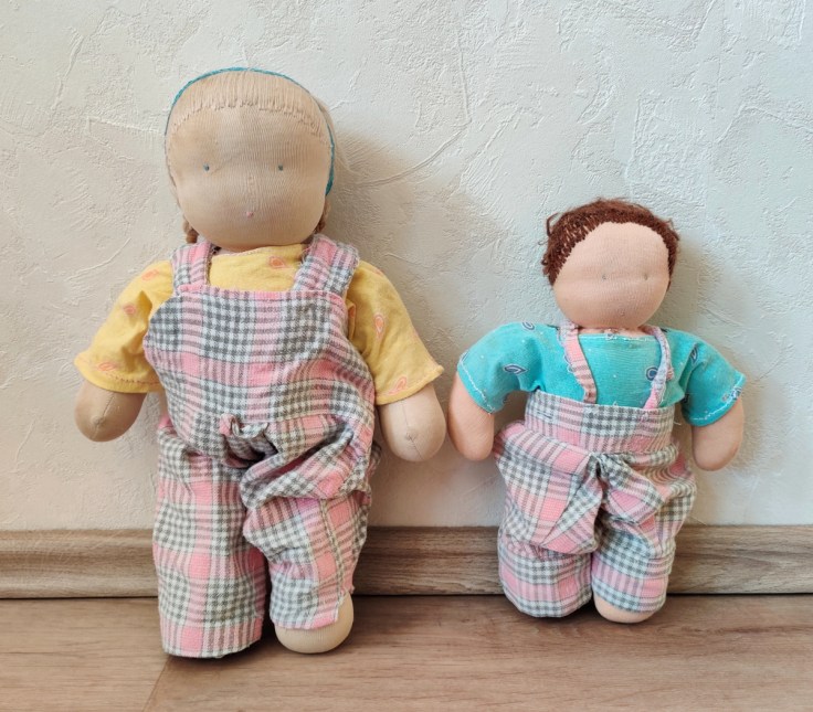 Kaksi Steinernukkea 1980- ja 1990-luvulta itse tehdyissä vaatteissa, nukeilla on samanväriset housut.