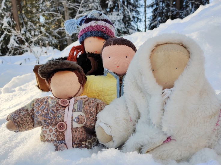 Neljä Steinernukkea 1980- ja 1990-luvulta ulkoilemassa lumisella pihalla itse tehdyt talvivaatteet päällään.