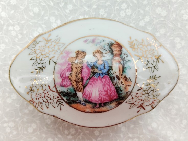 Posliinirasian kansi, jossa ihmisaiheinen koristekuva.