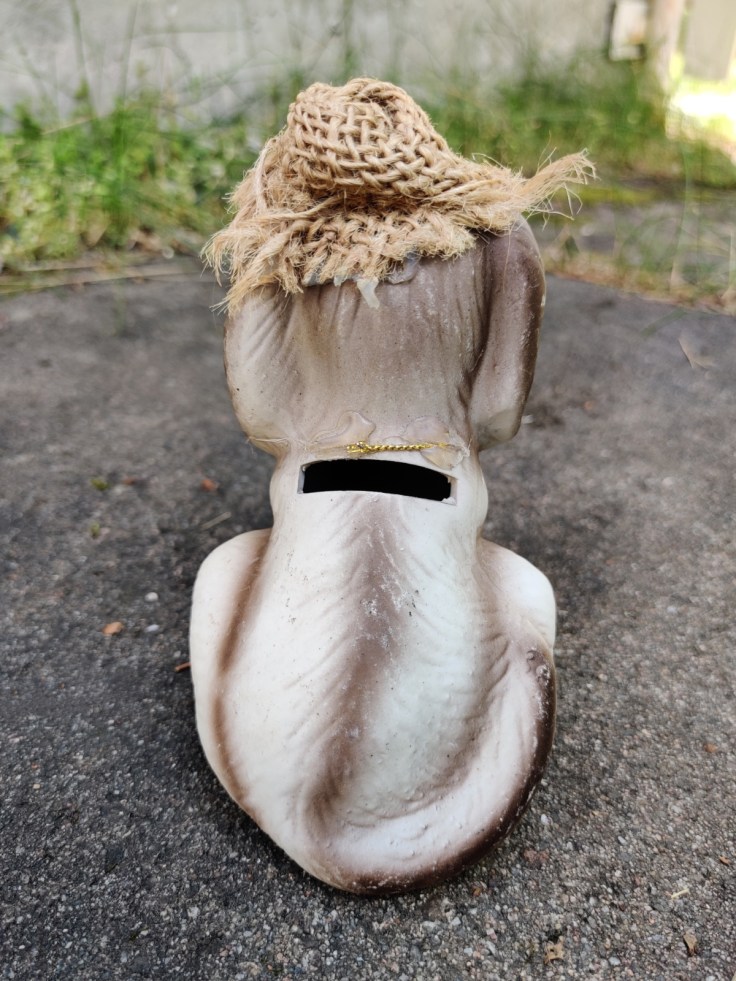 Keraaminen koiranmuotoinen kolikkopankki selkäpuolelta.