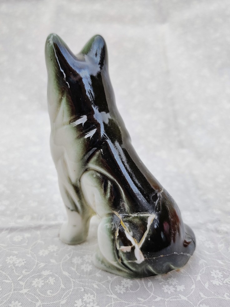 Särkyneen keramiikkakoiran selkäpuoli, palasia liimattu yhteen.