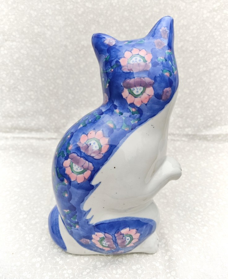 Iso istuva keramiikkakissa selkäpuolelta.