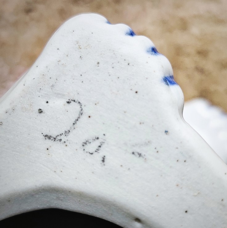 Käsin kirjoitettu hintamerkintä keramiikkafiguurin pohjassa.