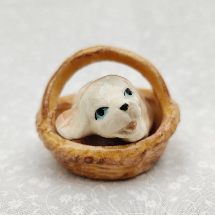 Keramiikkafiguuri koiranpentu korissa.