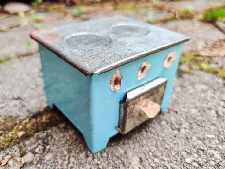 Peltinen nukkekodin hella 1950-luvulta hieman vinottain sivulta kuvattuna.