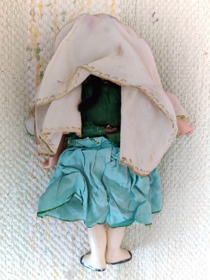 Kansallispukuinen nukke 1960-luvulta kuvattuna takaa.